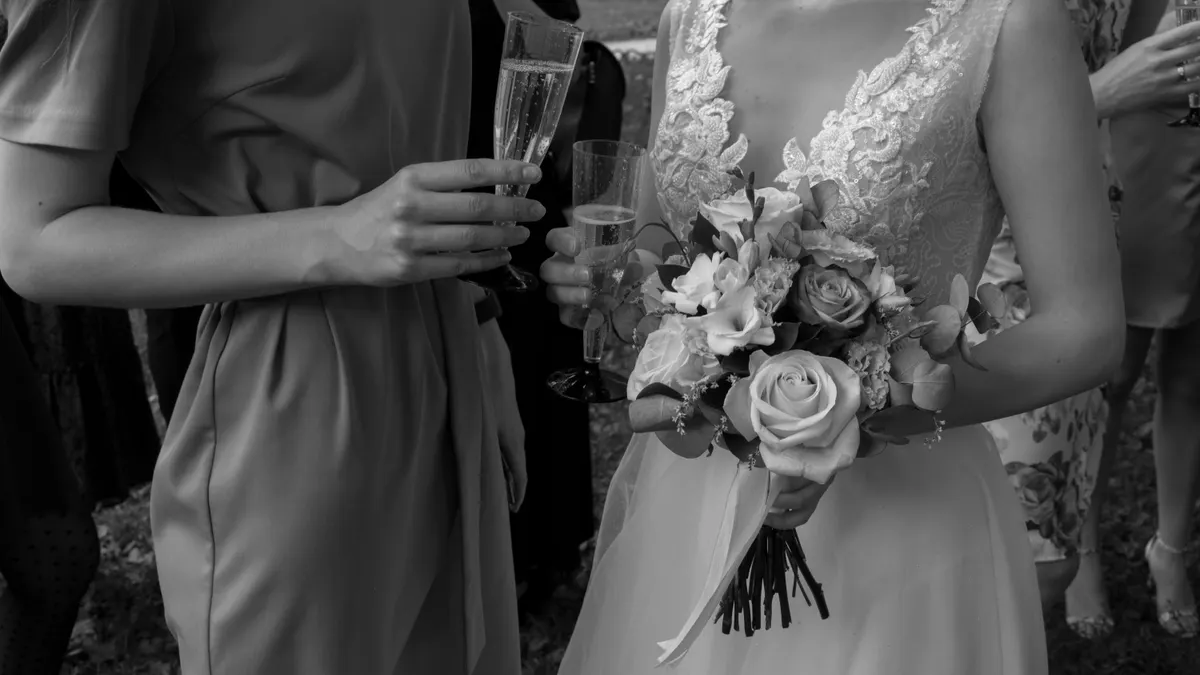 Une mariée tenant un bouquet et une coupe de champagne.
